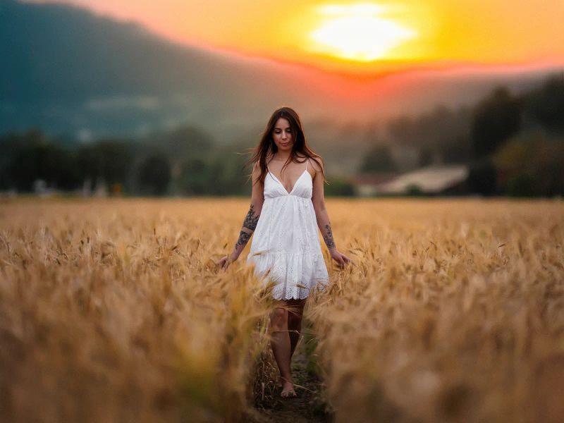 Lifestyle-Shooting einer Frau im weißen Sommerkleid in einem Kornfeld
