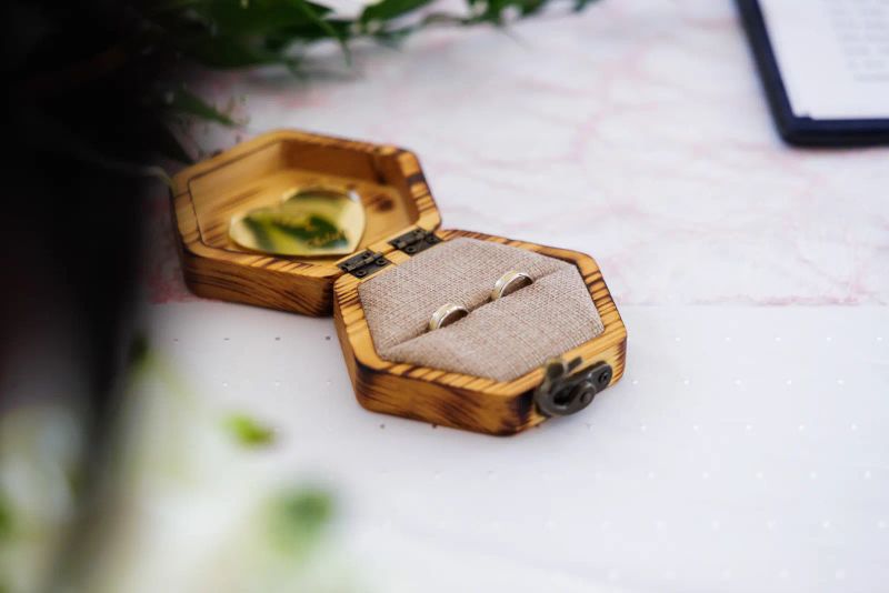Zwei goldene Trauringe in einer Holz-Ringbox — Detailaufnahme einer Hochzeit