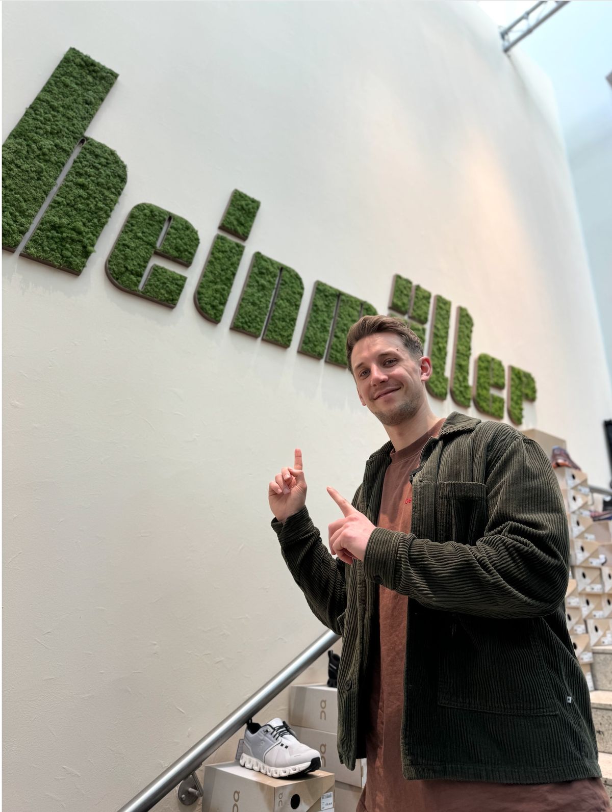 Philipp Ritz zu Besuch bei Schuhhaus Heinmüller vor dem grünen Unternehmensschriftzug